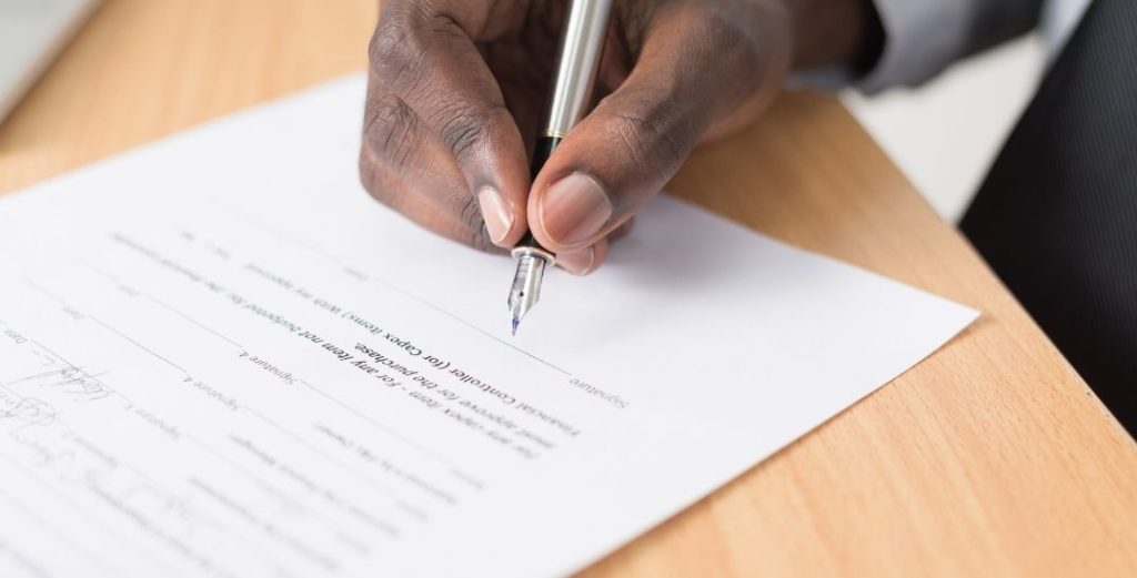 Man's hand signing contract document