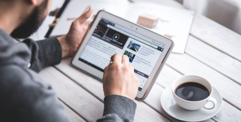 Man working on tablet with cup of coffee