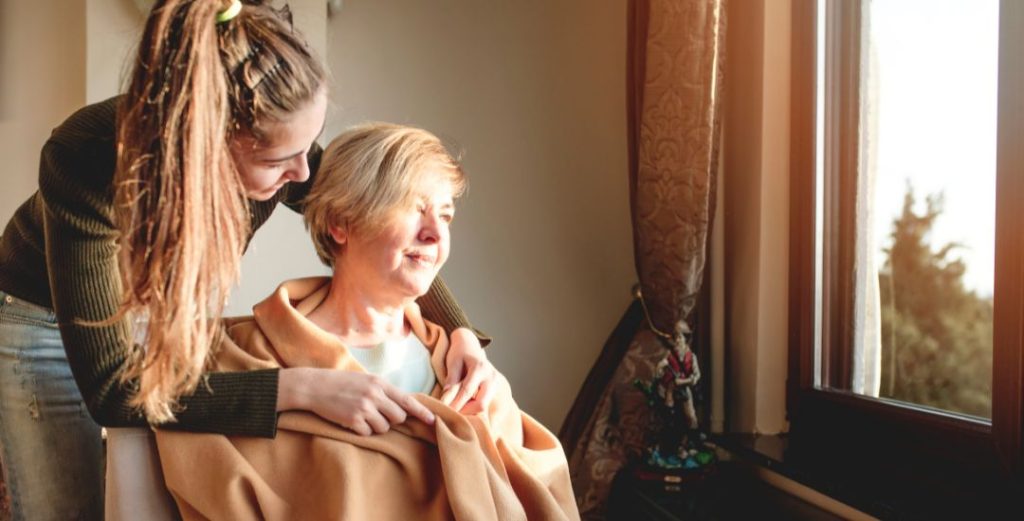 Young woman wrapping blanket around older woman